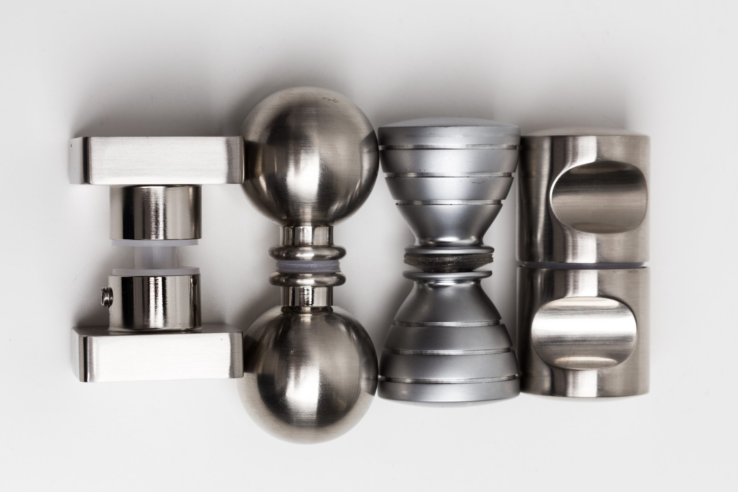 Assorted stainless steel and metallic mechanical parts arranged on a white surface showcasing industrial precision and modern design elements suitable for engineering projects.