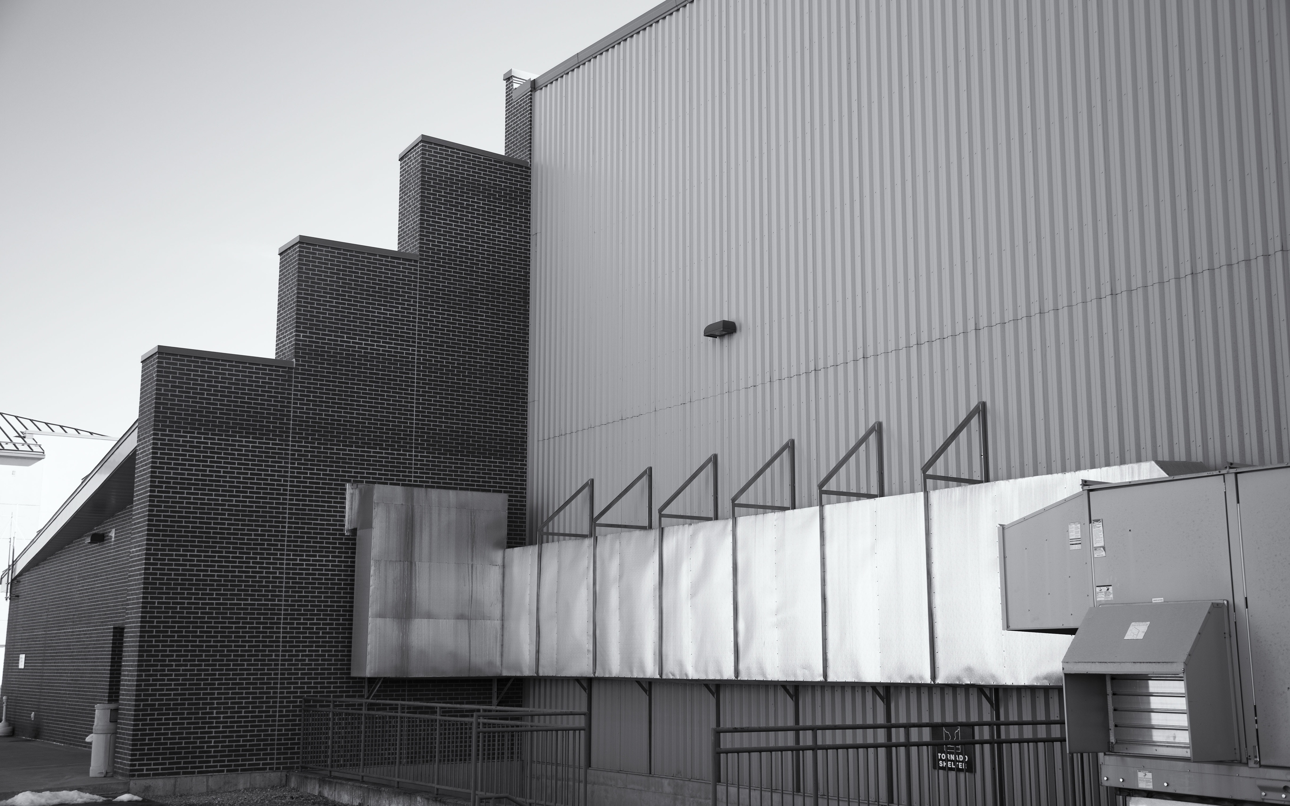 Industrial & Manufacturing Spaces like this building exterior showcasing metal ventilation system and brickwork design under a clear sky ideal for architecture or construction industry content.